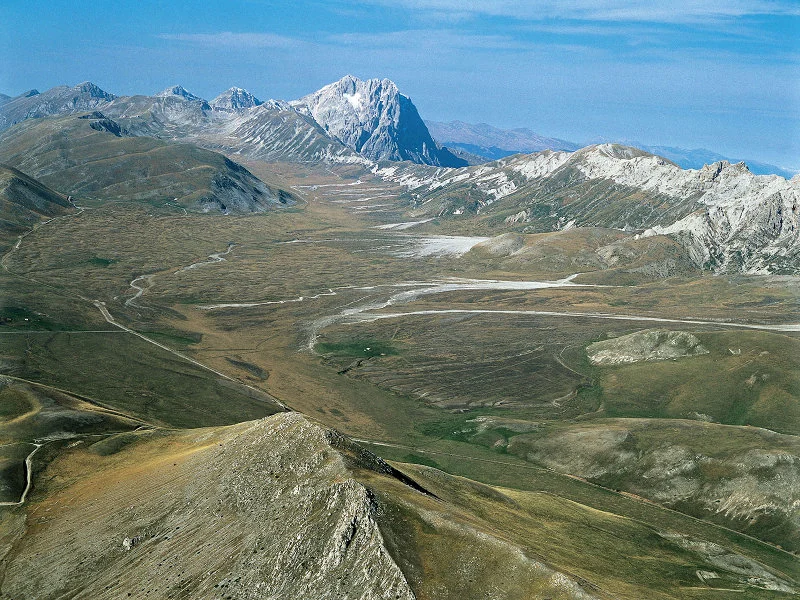 Veduta dall’alto dell’altopiano di Campo Imperatore, con i pascoli, le strade sterrate e sullo sfondo il Corno Grande
